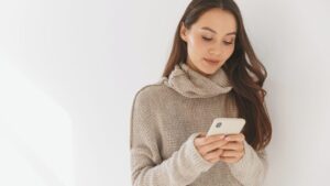 Frau schaut auf ihr Smartphone und reflektiert über das Gefühl, nicht gut genug zu sein.